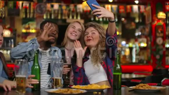 一群不同的朋友在酒吧里用手机自拍视频的预览图