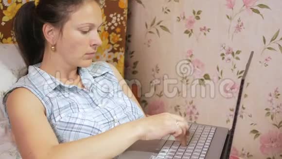 年轻女子在家里的沙发上用笔记本电脑工作小心地按下触摸板视频的预览图