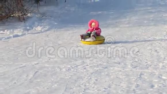 小女孩在阳光明媚的冬日从山上滑下雪管视频的预览图