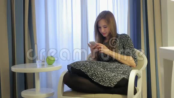 女性使用智能手机坐在扶手椅上吃绿苹果视频的预览图