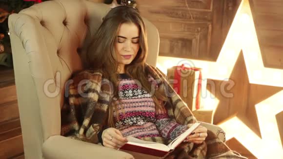 女孩正坐在圣诞树旁看书视频的预览图
