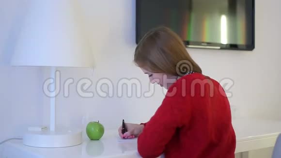 年轻女子在白色桌子上写记事本视频的预览图