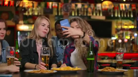一群不同的朋友在酒吧里用手机自拍视频的预览图