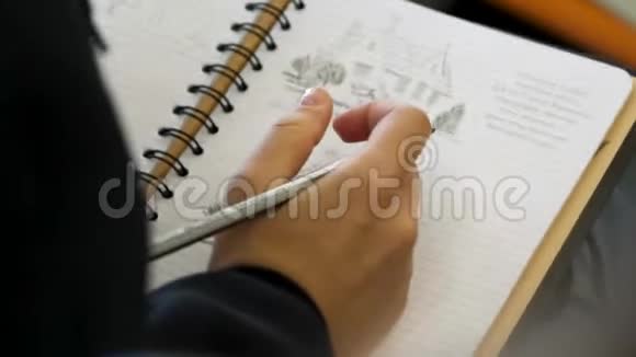 手拿铅笔在笔记本上写字或画画成人用软尖铅笔着色女性手绘视频的预览图