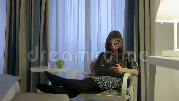 女性在酒店房间使用平板电脑喝玻璃水视频的预览图