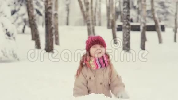 可爱的小女孩在雪地里玩耍把雪花扔起来视频的预览图