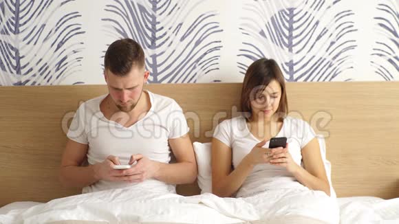 快乐的一对夫妻在床上用手机建立社交网络视频的预览图