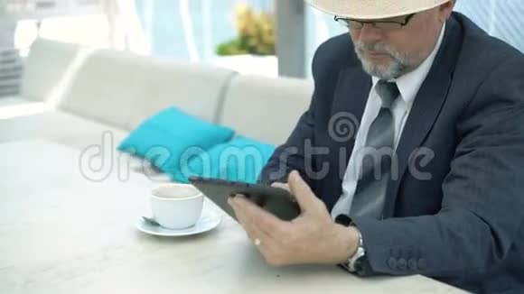 老商人在咖啡馆里用平板电脑喝咖啡4K视频的预览图
