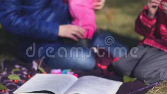 秋天公园野餐时两个朋友和孩子们在草地上玩耍视频的预览图