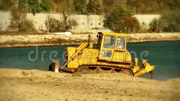 黄色推土机拖拉机在海滩上举起沙子视频的预览图