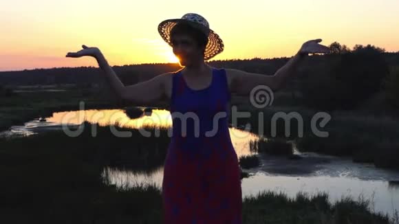 夕阳下微笑的女人在湖畔跳舞视频的预览图