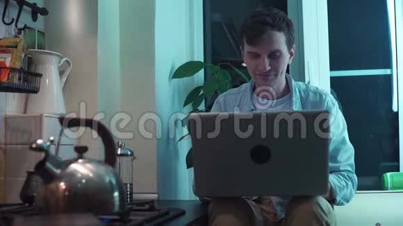 一个年轻人用电脑坐在厨房里烧水壶视频的预览图