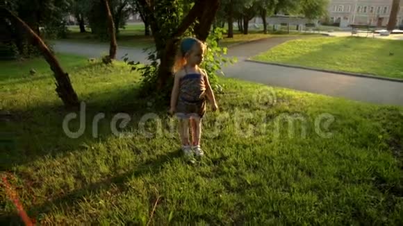 夏天日落时小女孩在公园的草坪上散步视频的预览图