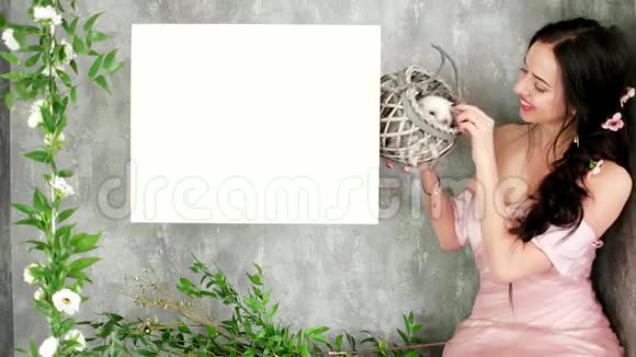 美丽的微笑女人摆姿势春天的照片会议抱着可爱的白兔在柳条篮子视频的预览图