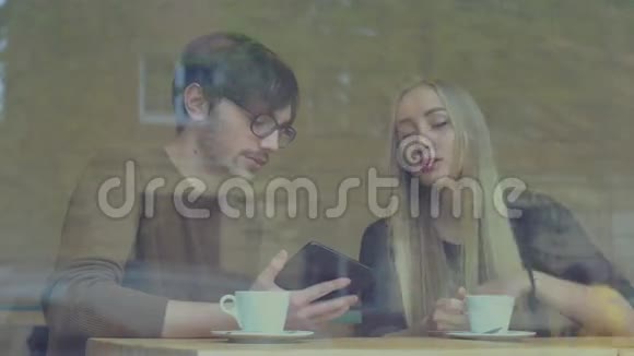一对年轻夫妇在咖啡厅里用平板电脑视频的预览图