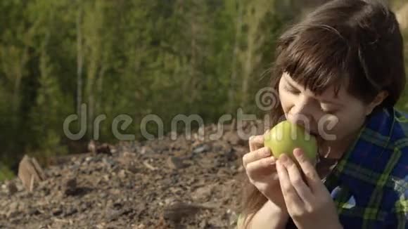 一个旅游女孩坐在山上在夏天吃一个绿色的苹果视频的预览图