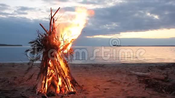 日落时分在河岸燃烧的帐篷形式的篝火视频的预览图