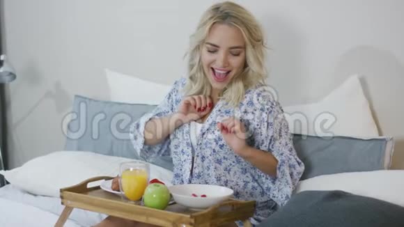 微笑的女人在床上吃早餐视频的预览图