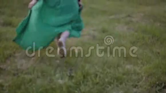 年轻的黑发女人在温暖的夏日快乐地逃跑穿着绿色衣服的漂亮女人视频的预览图