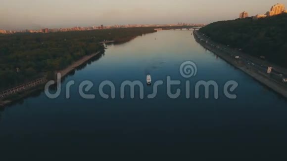 日落时分船沿欧洲河城附近的河流航行视频的预览图
