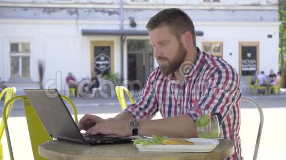 年轻人在咖啡馆午餐时写手提电脑视频的预览图