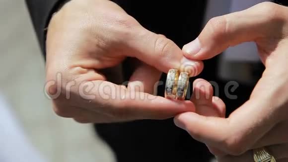 男人手里拿着两枚结婚戒指把它们转过来视频的预览图