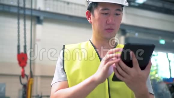 年轻的亚洲男性工厂工人使用数字平板电脑视频的预览图