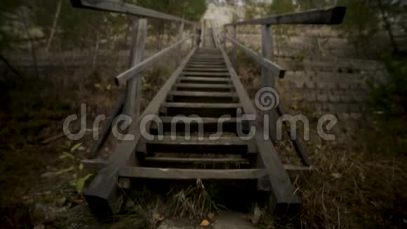 男人上楼梯录像两侧草地上的一座小山上的老木台阶上草的木楼梯视频的预览图