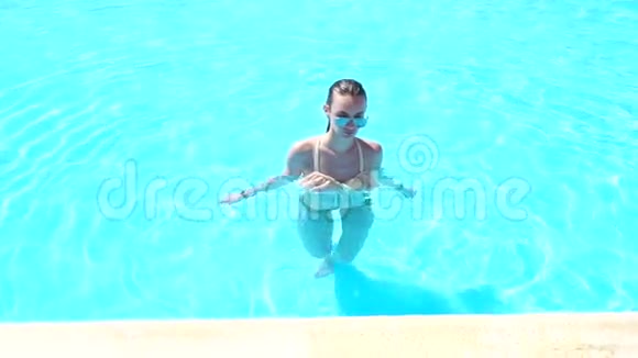 穿着泳衣和太阳镜的湿女人从游泳池里出来视频的预览图