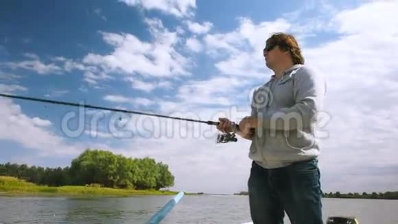 渔夫从河上的一艘船上钓到一条鱼在伏尔加河三角洲的船上钓鱼的人视频的预览图