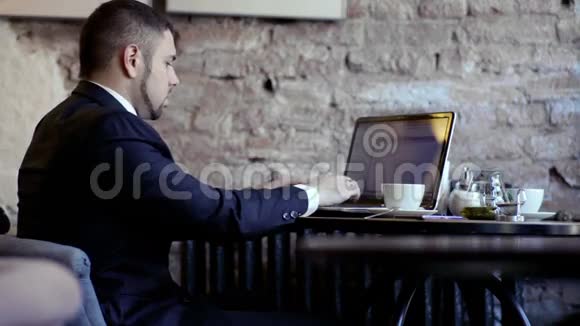 商人在咖啡馆里用笔记本电脑工作视频的预览图