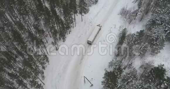 卡车在雪林的冬季乡村道路上行驶空中镜头视频的预览图