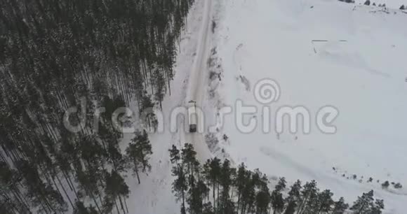 卡车在雪林的冬季乡村道路上行驶空中镜头视频的预览图