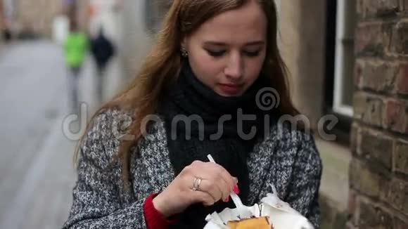 比利时布鲁日街上年轻美丽的女性游客吃比利时华夫饼的城市肖像视频的预览图