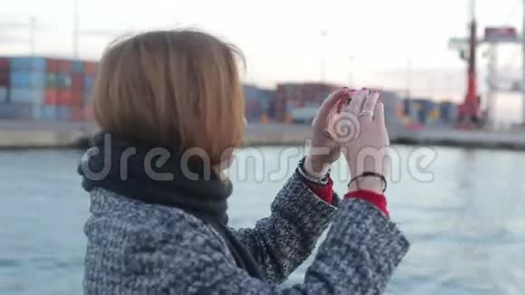 女性在甲板上拍摄港口基础设施照片视频的预览图