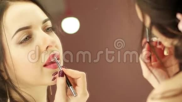 漂亮的年轻女士在镜子前涂粉红色唇膏女人化妆的特写视频的预览图