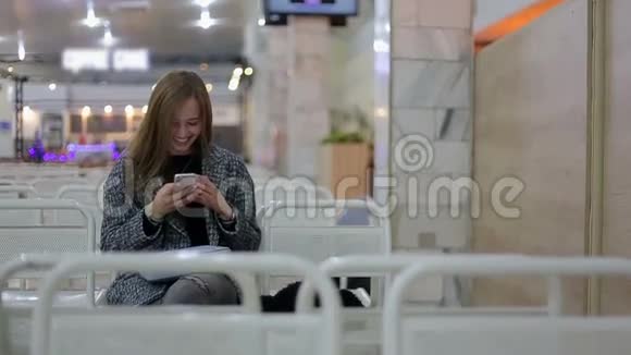 年轻女子带着智能手机在候机楼门口等候空中旅行的概念年轻的休闲女商人坐着视频的预览图