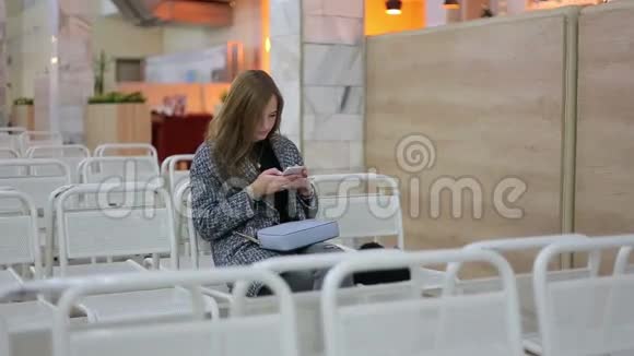 年轻女孩在机场打智能手机旅行概念与年轻休闲女士坐手提包视频的预览图