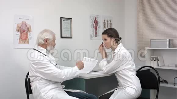 老年医生和年轻女性医生心电图医学讨论视频的预览图