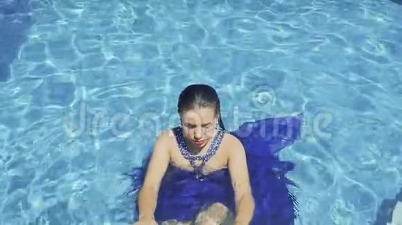 穿着蓝色衣服的漂亮模特在蓝色游泳池游泳视频的预览图