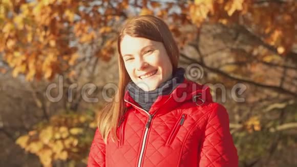 快乐的微笑女人享受大自然站在秋天的公园里年轻漂亮的女人在镜头前微笑视频的预览图