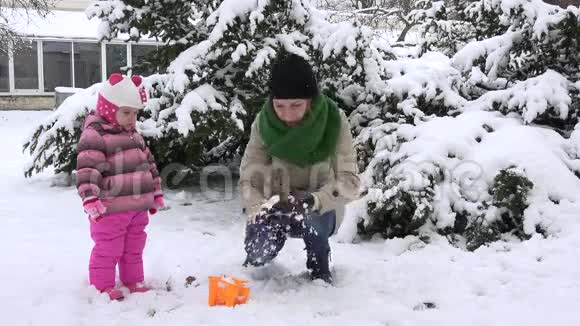 幸福的女人和女孩女儿一起玩第一个冬天的雪雪花飘落视频的预览图