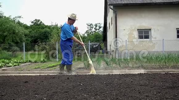 农夫在花园的小路上用一把大扫把扫地视频的预览图
