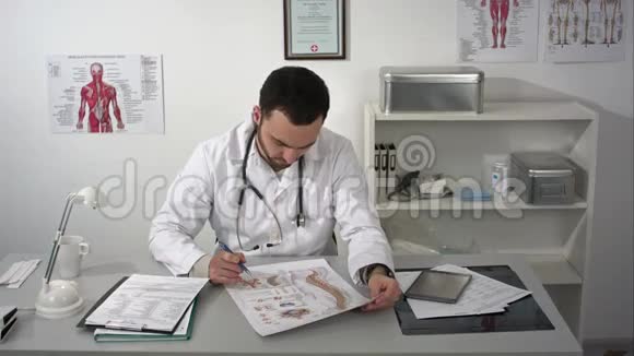 物理治疗师在他的练习中他桌上的脊椎柱海报视频的预览图