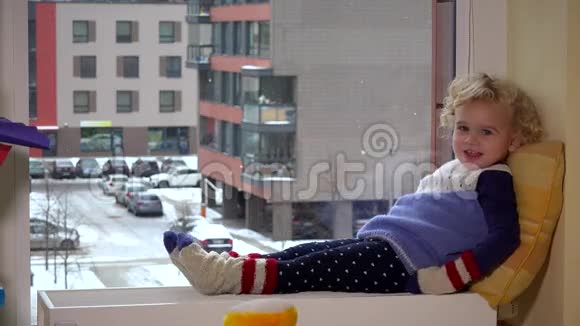 小女孩坐在暖气片上看着平坦的房子院子视频的预览图