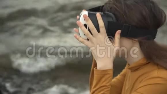 一个年轻的女人在强大的波浪旁边使用虚拟现实眼镜视频的预览图