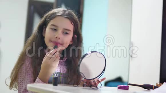 小女孩在室内涂口红女学生在镜子前涂红唇膏视频的预览图