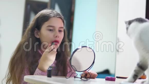小女孩用室内口红涂嘴唇女学生在镜子前涂红唇膏视频的预览图