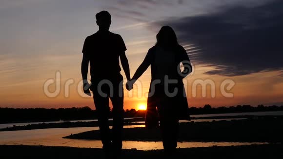 恋爱中的情侣在河边散步在日落时牵手高清1920x1080慢动作视频的预览图