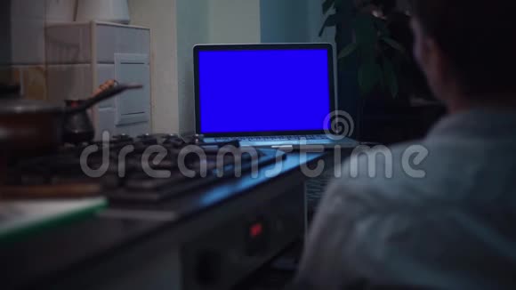 一个人在灶台附近的厨房里看色度键笔记本电脑显示器视频的预览图